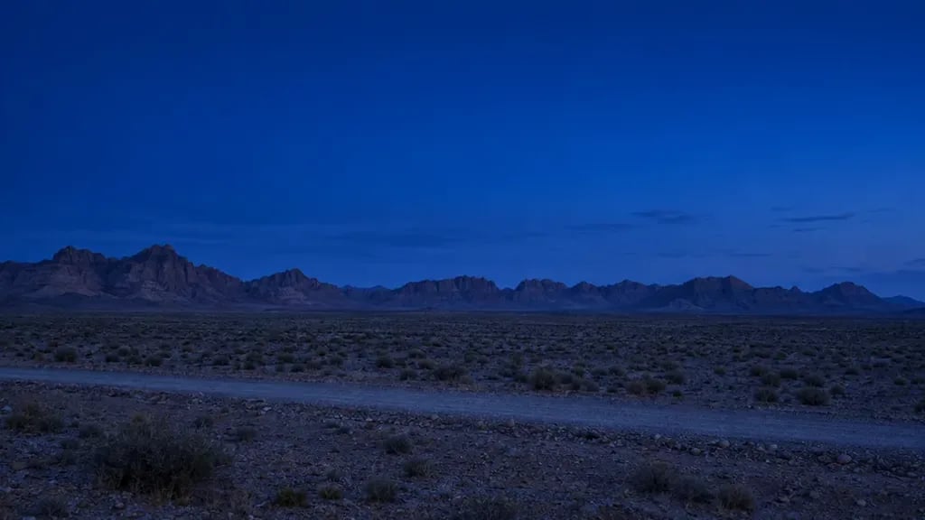 Leere Felswüste mit fernen Sandsteinrücken unter blauem Abendhimmel