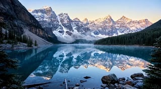 The same mountain lake, snowy peaks and evergreens after image adjustments that deepen contrast, balance highlights and enrich color.