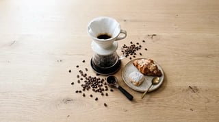 The same pour-over coffee, beans and pastries on the wooden table with cooler color balance, softer highlights and sharper detail.