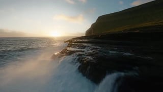 La stessa costa al tramonto con un bagliore morbido attorno alle alte luci.