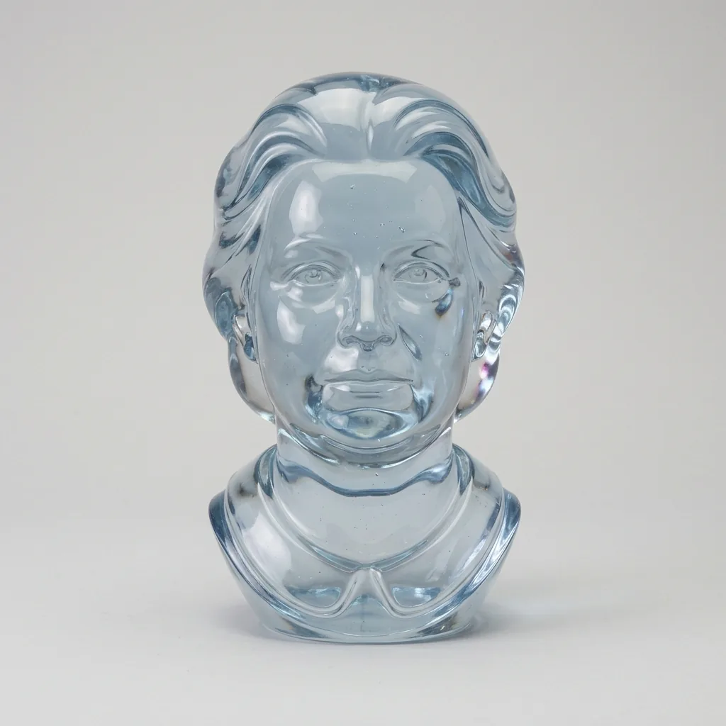 Portrait bust of a woman with swept hair and a simple collar, entirely formed from pale blue and clear glass against a gray background